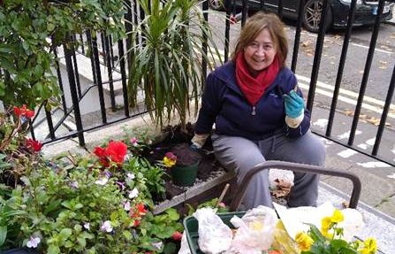 C&C resident Myriam poses in her front garden as she plants some flowers. She uses gardening to help with her feelings of loneliness. Image credit: CCHT