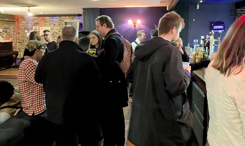 Several people stand by a bar at a London Independent Film Festival networking event.
