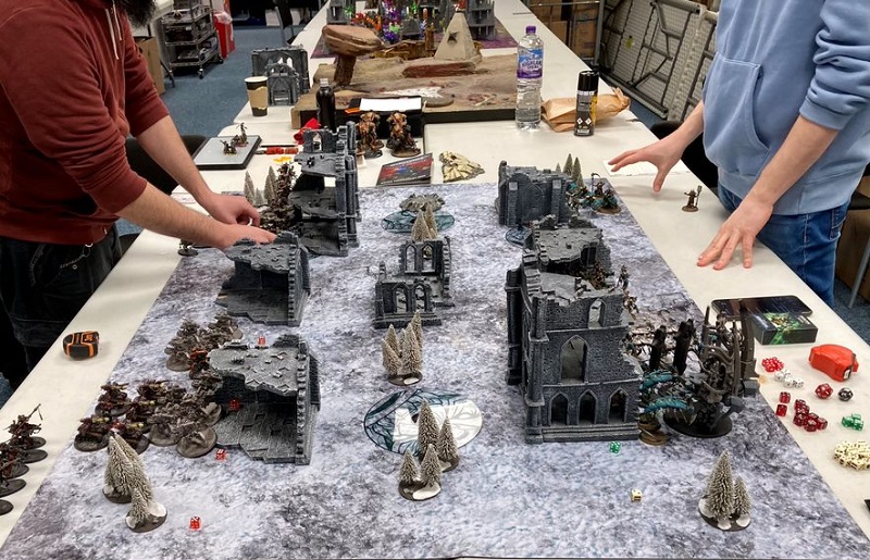 Two gamers in the process of setting up a Warhammer table