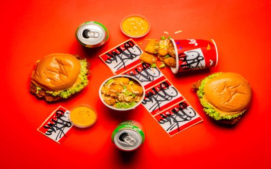 The burger and tater tots from the Whyte x Jollibee event on a red background