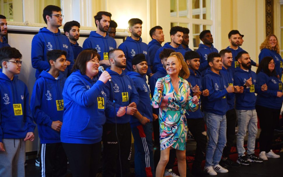 A choir in blue hoodies with two lead singers at the front