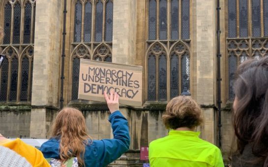 Person holding up protest sign in front of Bristol cathedral