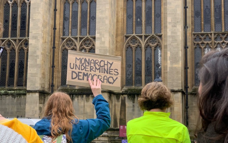Person holding up protest sign in front of Bristol cathedral