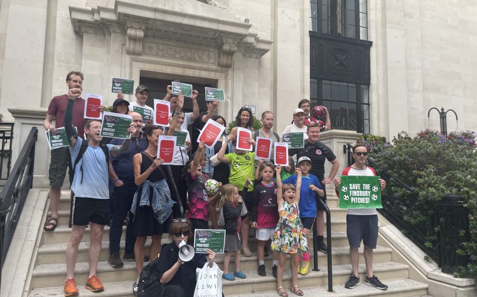 An image of protestors standing outside of Islington Town Hall holding up red cards