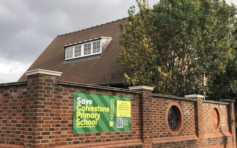 A sign saying Save Colvestone Primary School on the playground wall