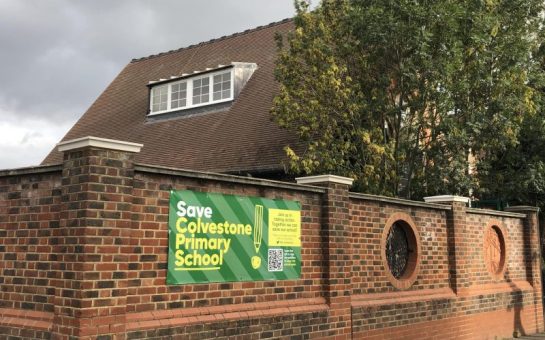 A sign saying Save Colvestone Primary School on the playground wall