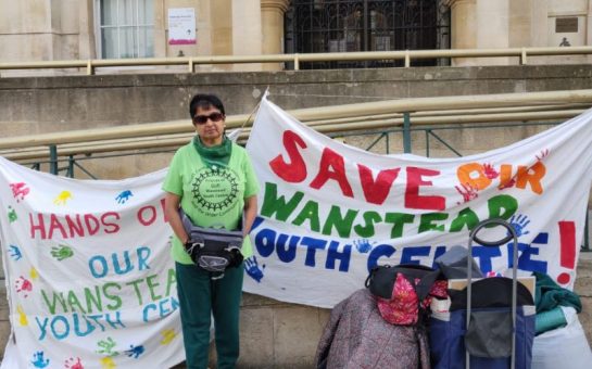 A woman stands outside a town hall protesting