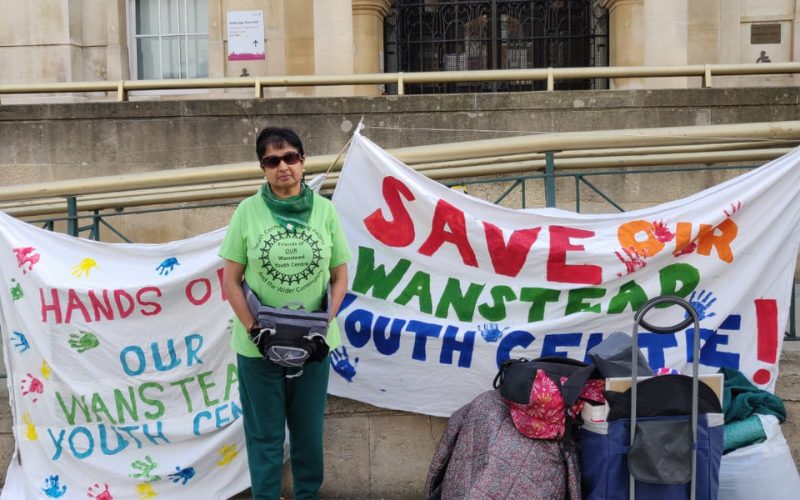 A woman stands outside a town hall protesting