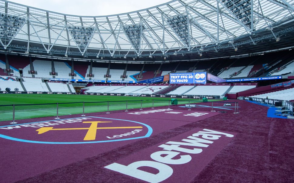 Pitch side image of the the London Stadium interior with the West Ham United badge in view.