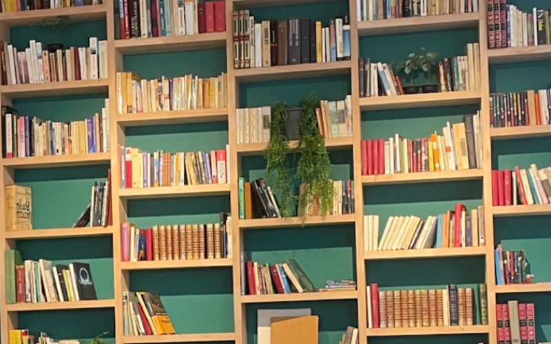 Multiple bookshelves on a wall filled with books.