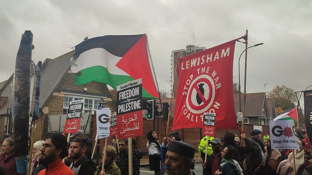 Protestors marching through Lewisham with Palestinian flags and a large banner for the Lewisham Stop the War Coalition