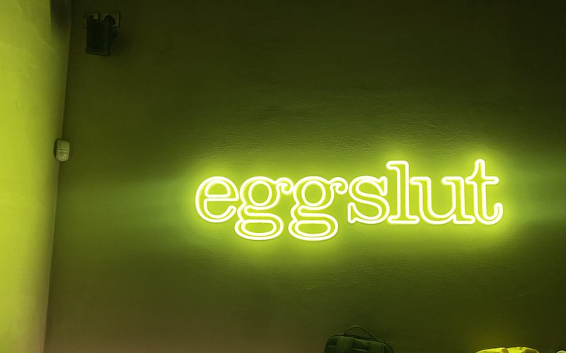 A neon sign reading 'eggslut' in eggslut Stratford
