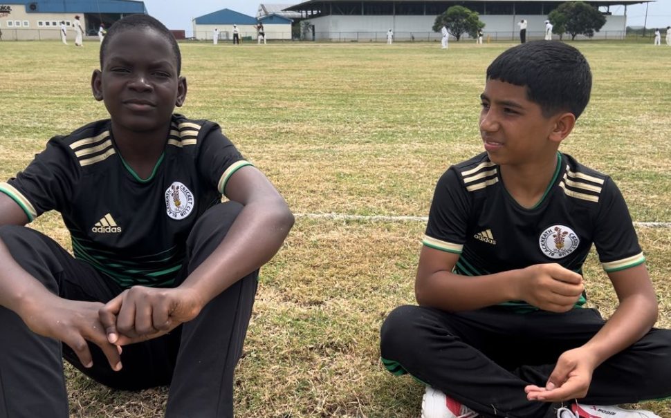 Two boys sitting on cricket pitch