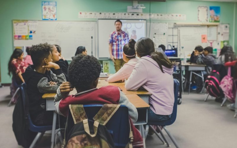 Group of children in school classroom facing teacher