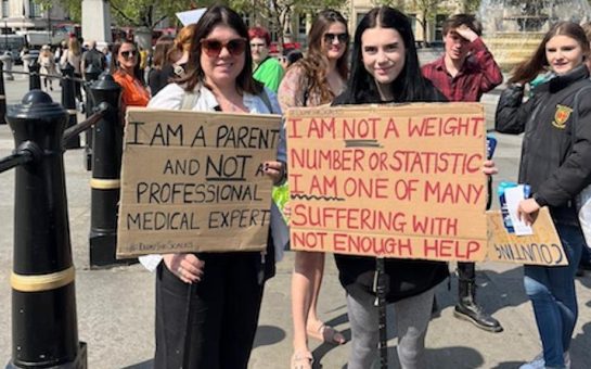 Two women holding up signs around eating disorders