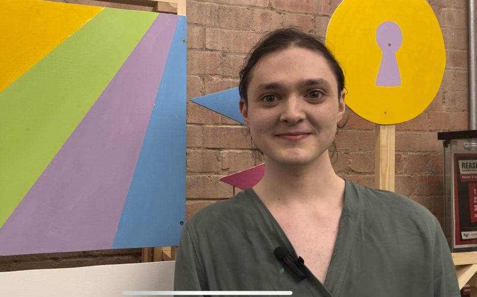 Person smiling at camera in front of colourful display