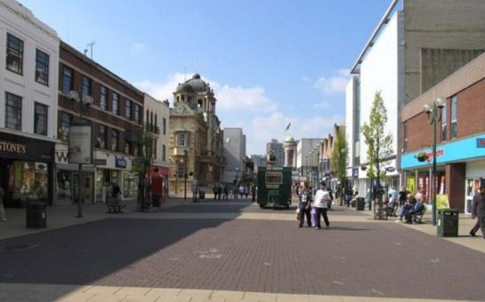 A busy Redbridge town centre with the sun shining and buildings casting shadows.