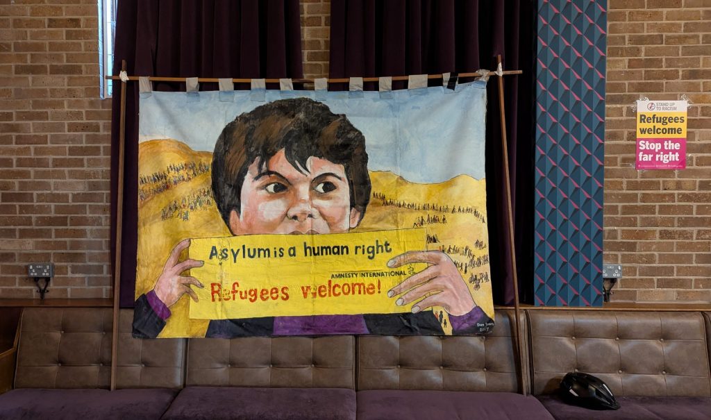 Handpainted poster celebrating refugees and saying "Asylum is a human right, refugees welcome"