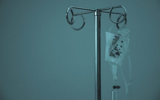 An IV drip hung up in a dark room