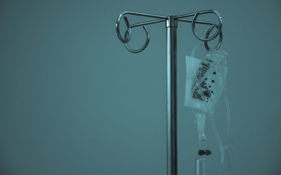 An IV drip hung up in a dark room
