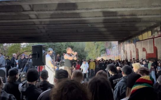 An image of a group of punk fans watching a gig under a motorway in Hackney Wick
