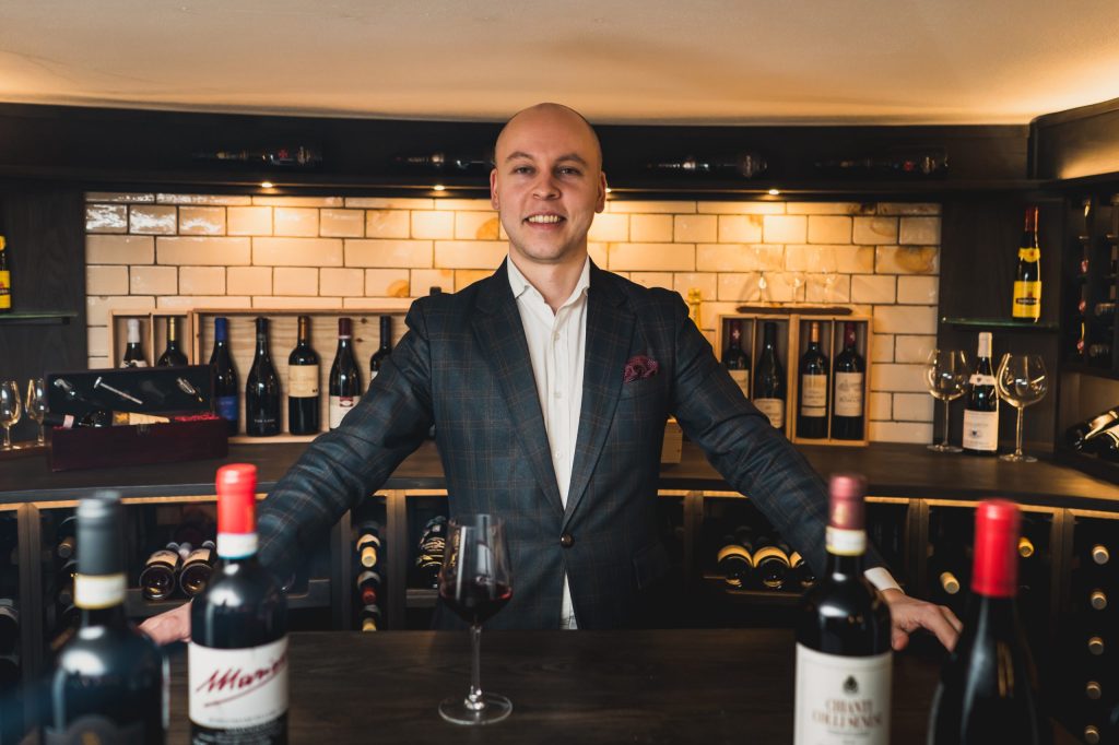 Znutins poses with wine at his former workplace