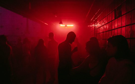 Group of people inside a techno club surrounded by red mist