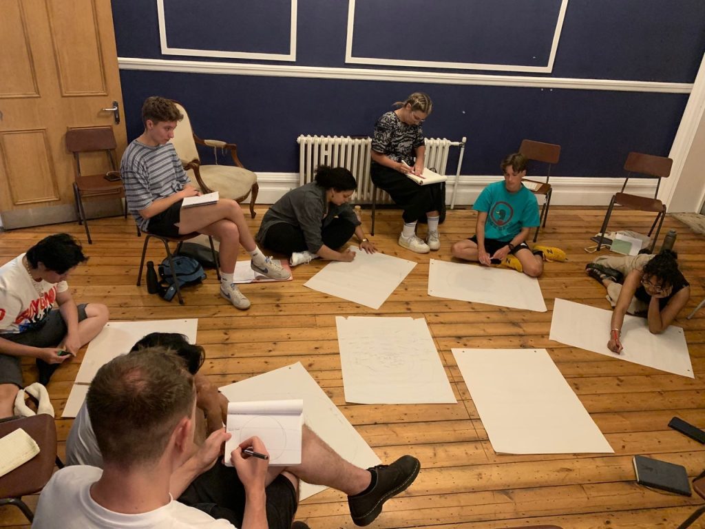 Young writers sat on the floor with big pieces of paper as part of the Squint Playwriting Award partially funded by Arts Council England