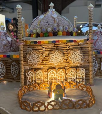 This image shows a huge gingerbread building with an ice rink out the front, and two gingerbread people skating!