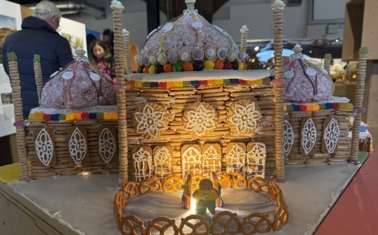 This image shows a huge gingerbread building with an ice rink out the front, and two gingerbread people skating!
