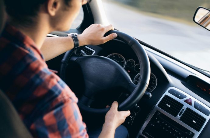A young man sits at the steering wheel of a car