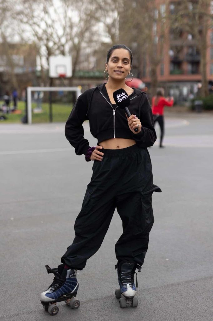 Presenter Lillie Almond wearing a black tracksuit, rollerskates and holding a microphone