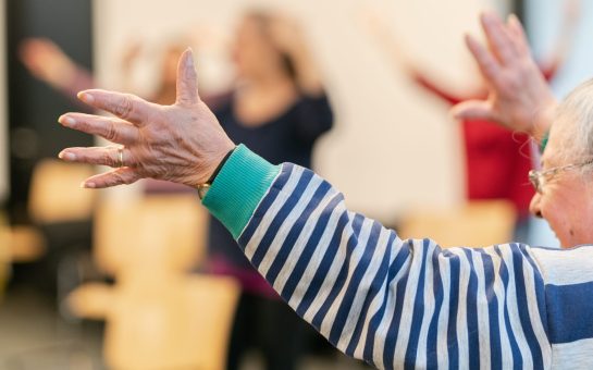 Lady wearing striped top is dancing with her arms up