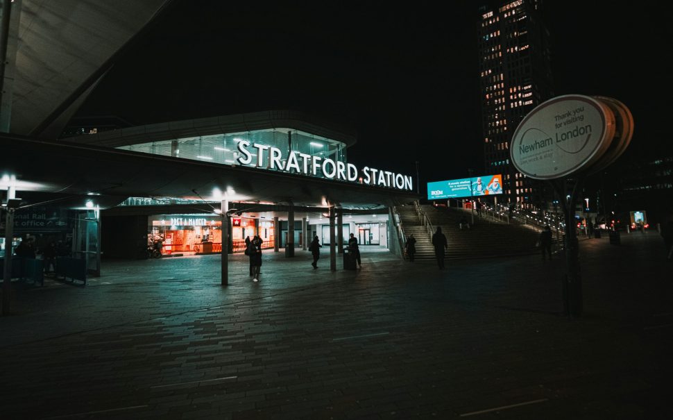 Stratford Station outside at night with Newham sign to one side