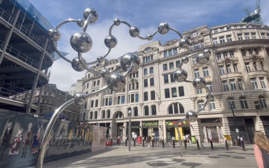 A picture of a sculpture outside a major London station featuring towering reflective silver spheres connected by twisting arches.