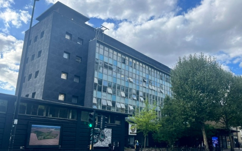 Large black building with blue windows, art pieces on street-level