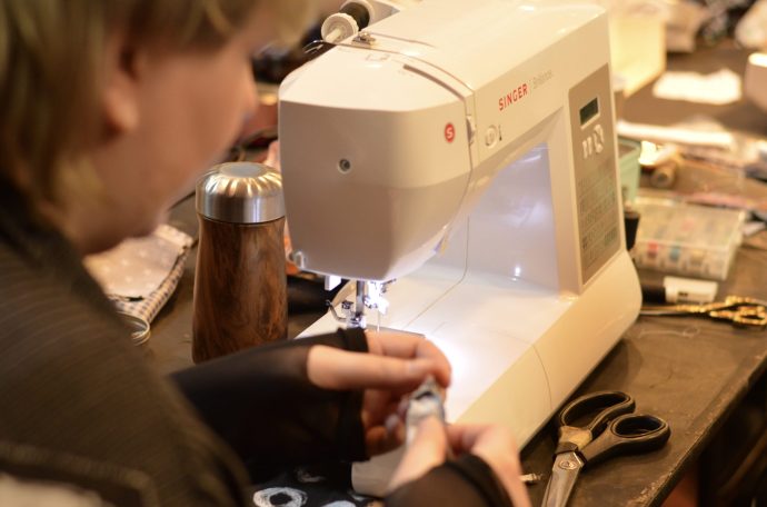 A woman uses a sewing machine to repair clothes