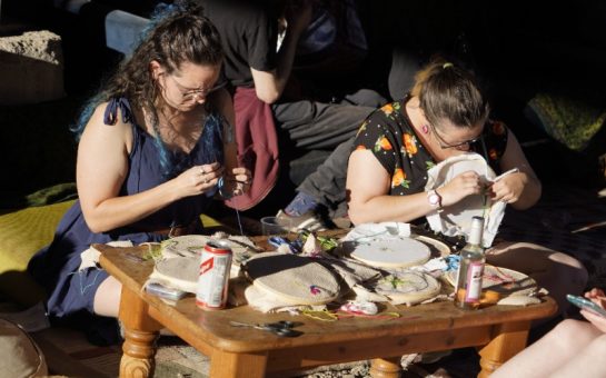 An image of people sewing by hand at a Repair Café