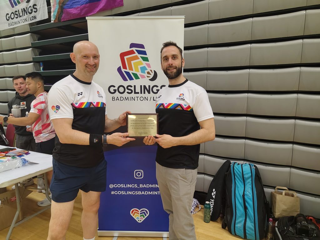 Goslings LGBT+ badminton co-chairs hold up a plaque to celebrate the club's 50th anniversary.